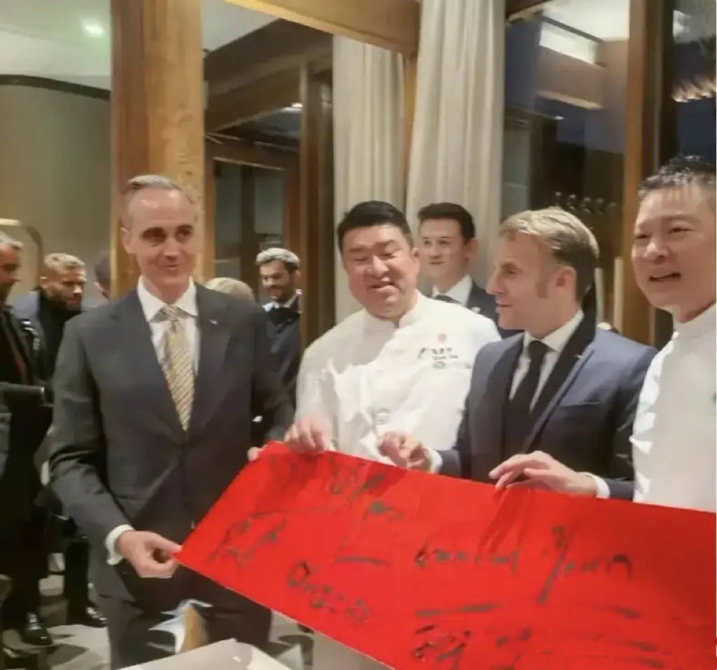 巩俐陪马克龙夫妇吃烤鸭，穿黑衣扎丸子头气场强，快六十岁还很美