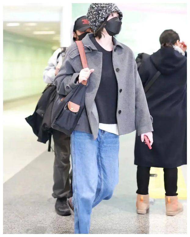 王菲休闲打扮,带着印花帽子,身穿灰色外套和牛仔裤,依然展现出53岁的