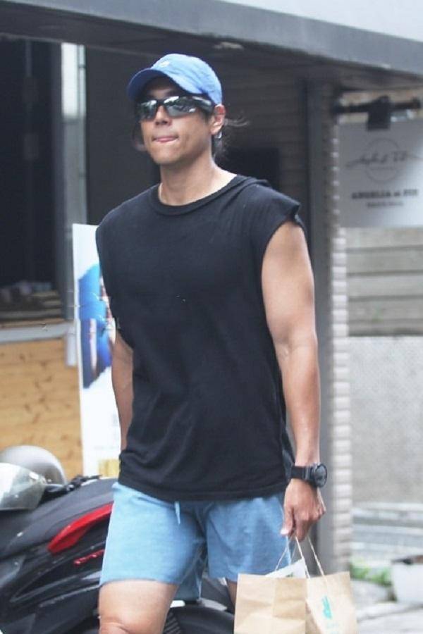 彭于晏头戴蓝色的鸭舌帽,身穿一身夏凉装,扎着马尾辫行走在大街上