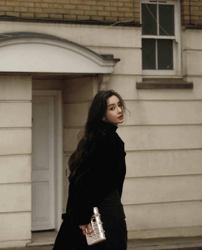 angelababy身穿黑色风衣,在熙攘都市中行走,回眸