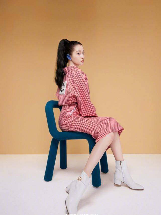 第五张是关晓彤的侧面全身照,她坐在椅子上,粉红色格子上衣加上包臀裙