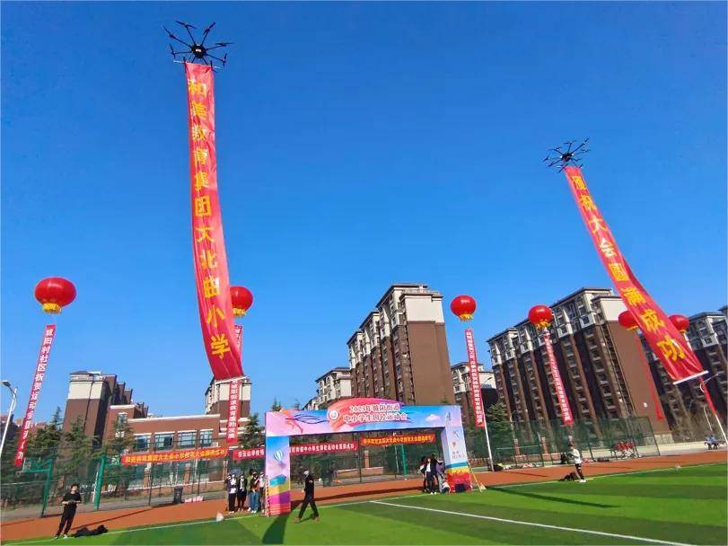 住全场的目光当横幅展开的一霎那两架无人机拉着横幅呼啸而起绿茵操场