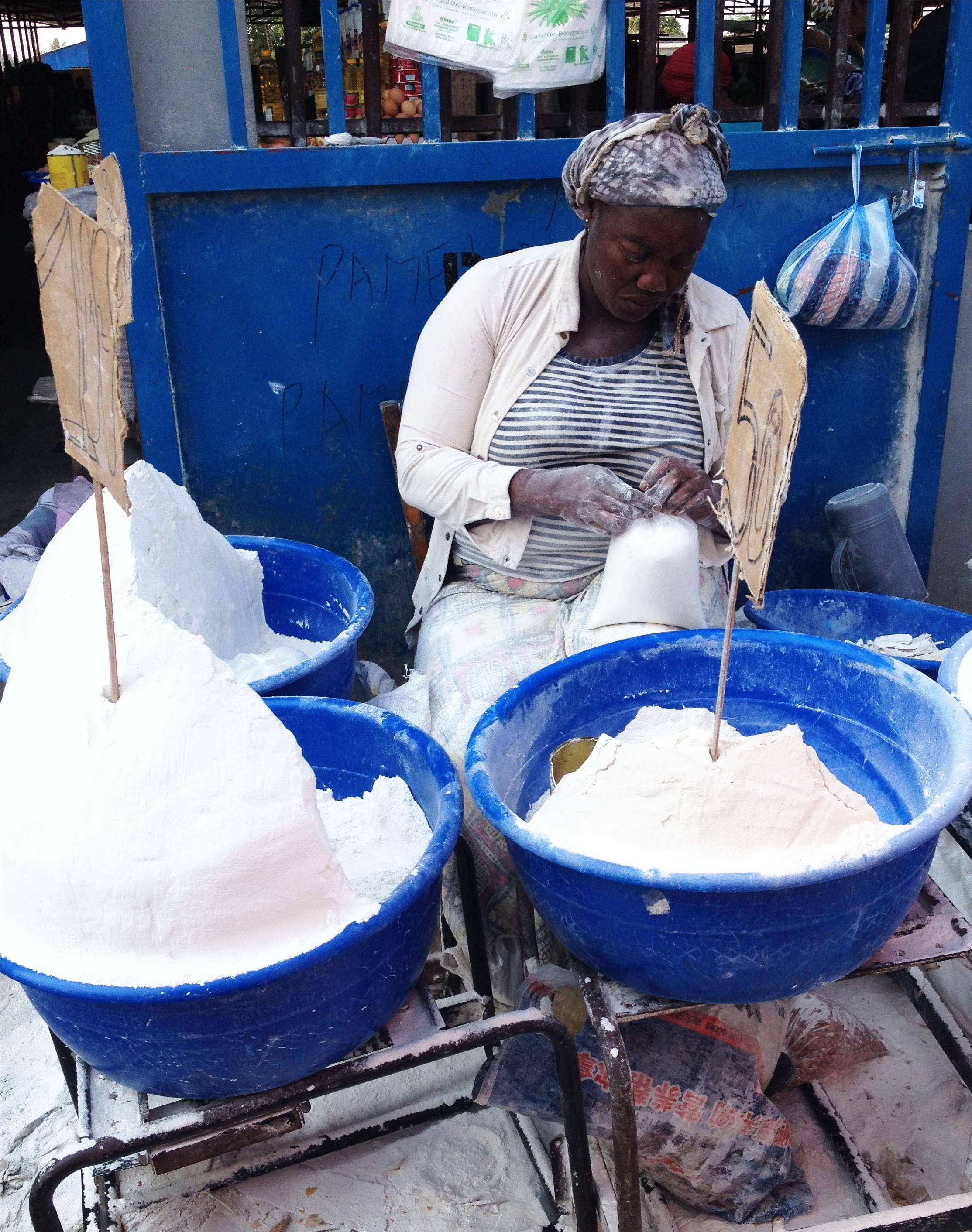 图四中卖白面的黑人女人正在精心地捆扎装好的面粉的口袋