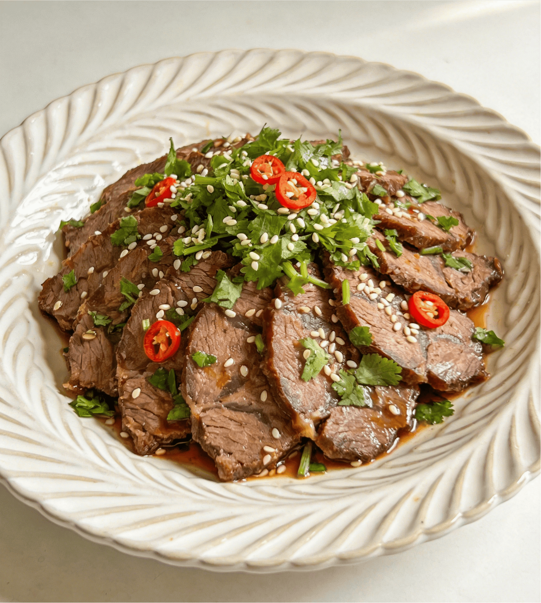 jimeng-2026-05-29-1729-清爽开胃的凉拌牛腱，一个精致的白色陶瓷盘子，盛放着切好的凉拌酱牛肉。上面撒着新鲜....png