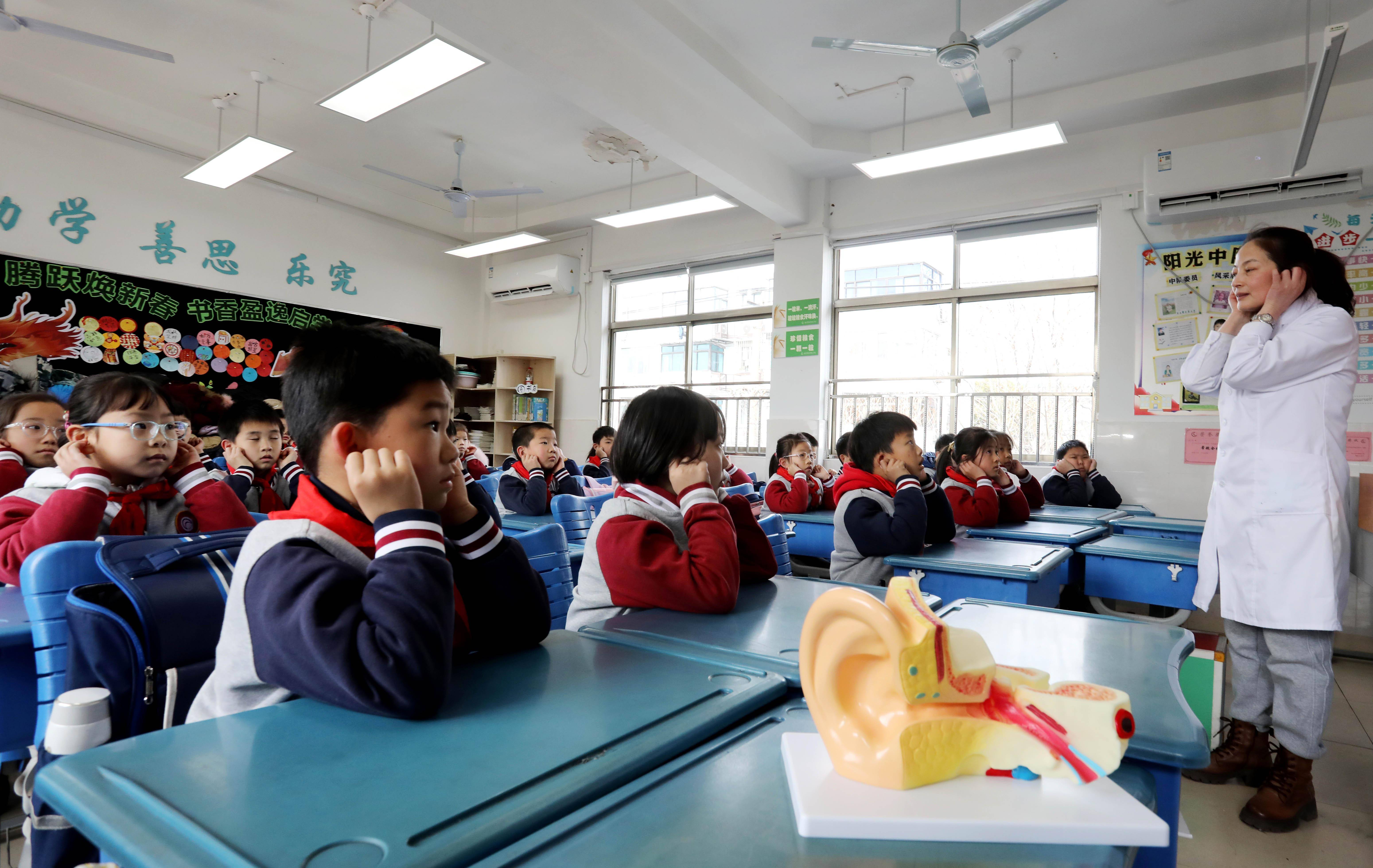 一村社区卫生服务中心医务人员在指导彩香实验小学的学生做耳保健操
