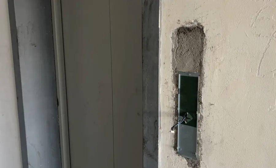 另一部电梯还在安装中,门前设有施工围挡,围挡内堆叠着配重块,电梯