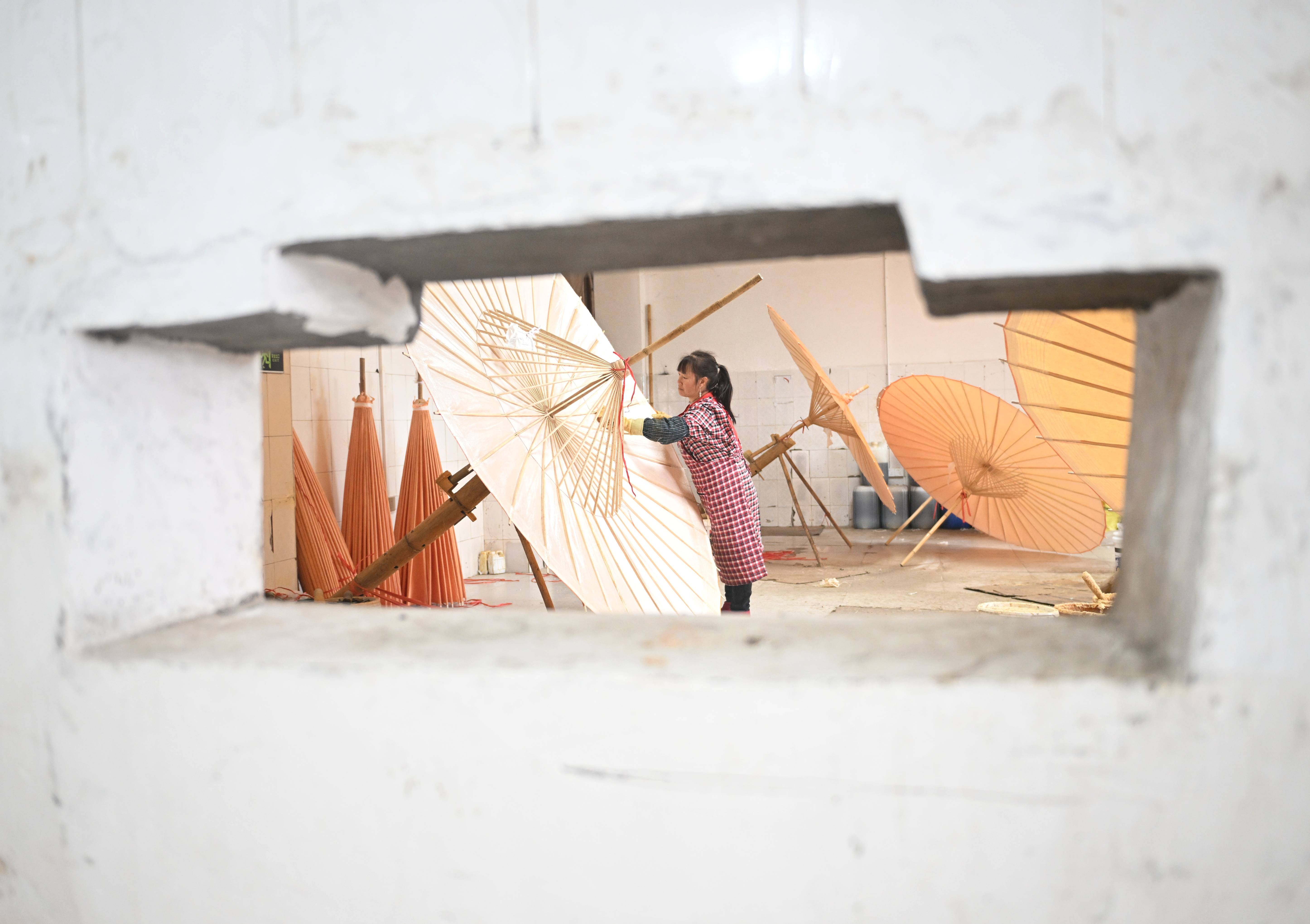 2025年2月11日,制伞师在为油纸伞上桐油