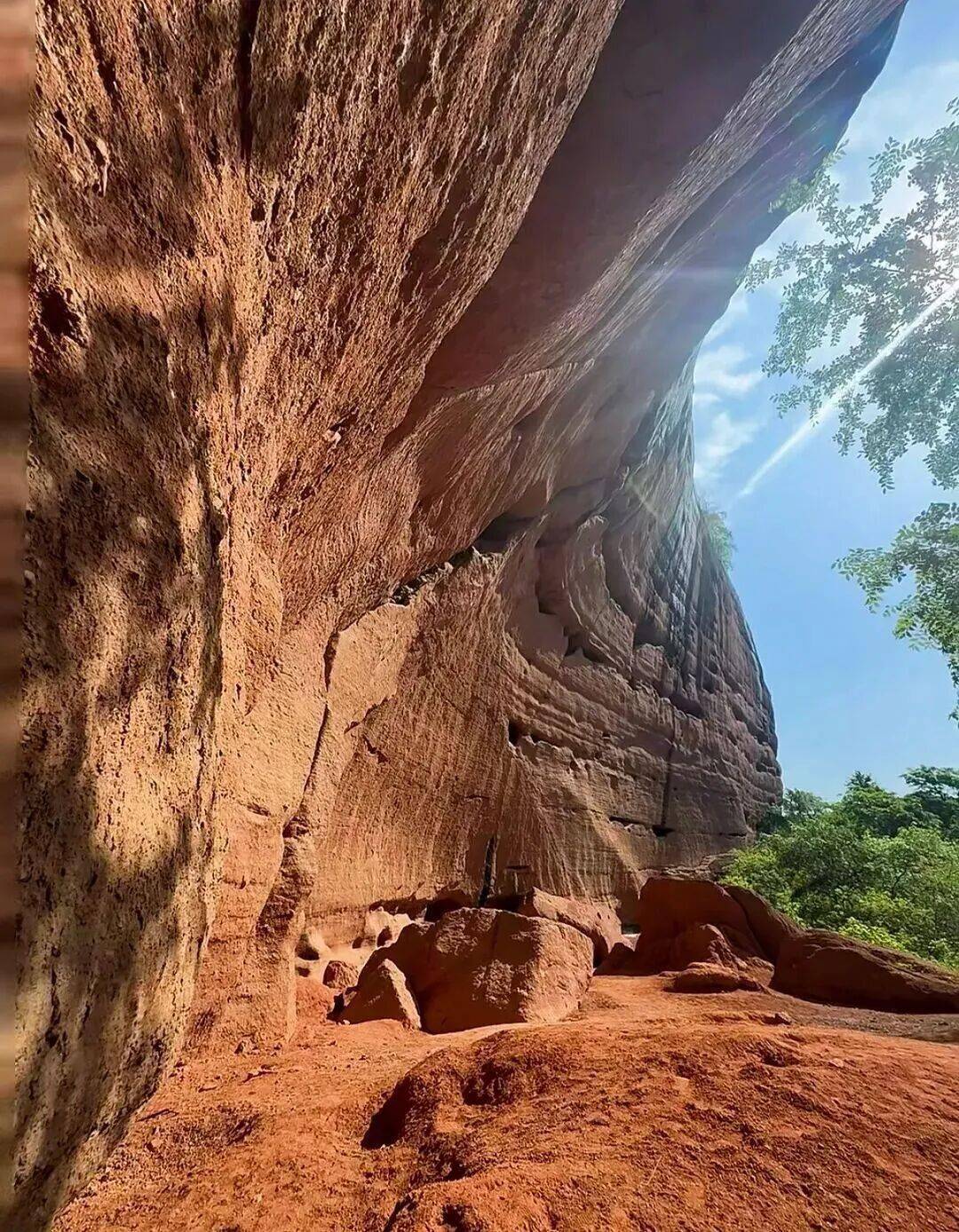 赭红色的丹霞岩壁层层叠叠风蚀出蜂窝状的孔洞在阳光照射下如火焰般